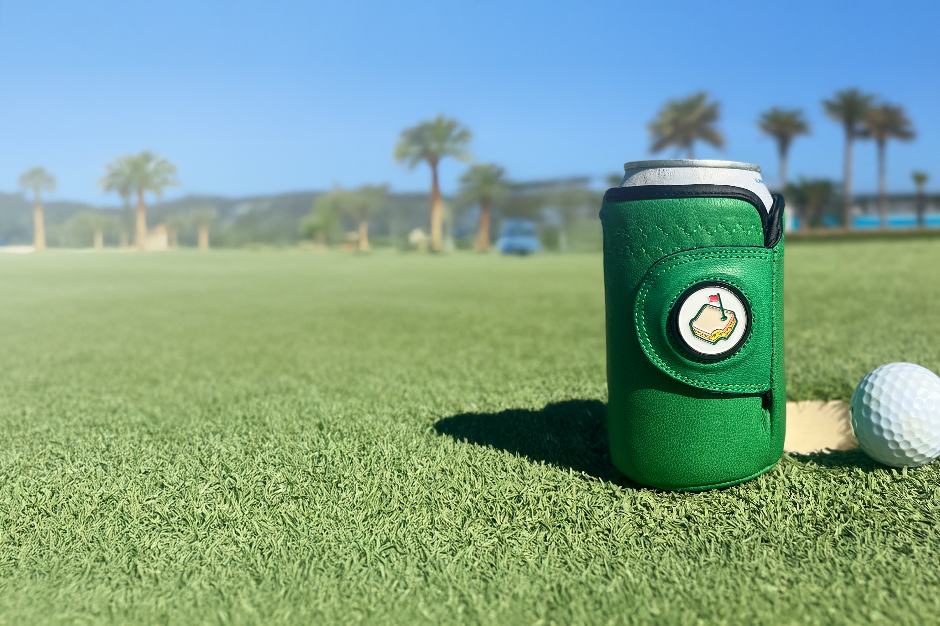 Masters green Gloozie golf glove coozie sitting on a golf course green with golf ball