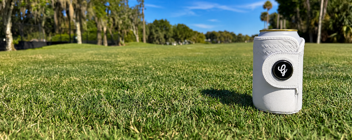 White Gloozie golf coozie on the grass of a sunny golf course